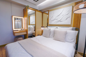 Small bedroom with queen bed centered on main wall, with gallery wall above tucked side